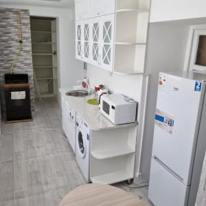 W kuchni znajduje się biała lodówka i kuchenka mikrofalowa. w obiekcie Квартира у моря w mieście Aktau