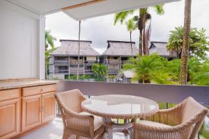 einen Balkon mit einem Tisch und Stühlen sowie ein Gebäude in der Unterkunft Waiakea Villas 2-207 in Hilo