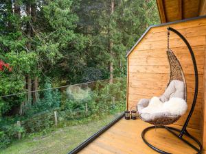 a swinging chair on a porch with a view of a forest at Luxurious holiday home with sauna in Krimml