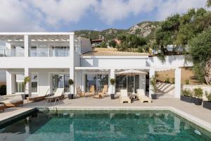 a villa with a swimming pool and a house at Nisos Villas Corfu in Benitses