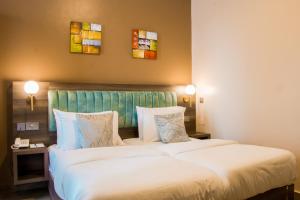 a hotel room with two beds and two paintings on the wall at Hotel Horizon Entebbe in Entebbe