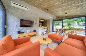 ein Wohnzimmer mit orangefarbenen Möbeln und einer Steinwand in der Unterkunft Family friendly house with a swimming pool Bajcici, Krk - 19311 in Vrh