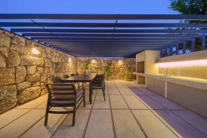 eine Terrasse mit einem Tisch, Stühlen und einer Steinmauer in der Unterkunft Family friendly house with a swimming pool Bajcici, Krk - 19311 in Vrh