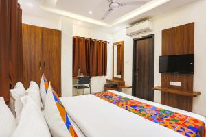 um quarto de hotel com uma cama e uma televisão em FabHotel Balaji Paradise em Indore