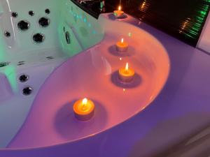four candles sitting in a bath tub with a bath tub at NG SuiteHome - Lille I Tourcoing Winoc - Balnéo - Netflix - Wifi in Tourcoing