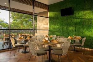 a restaurant with tables and chairs and a green wall at Swiss-Belinn Singkawang in Singkawang
