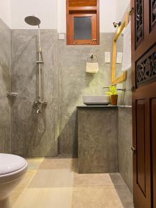 een badkamer met een douche, een toilet en een wastafel bij The Cozy Nest in Hikkaduwa