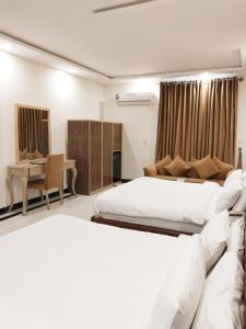 ein Hotelzimmer mit 2 Betten und einem Schreibtisch in der Unterkunft Royal Grace Guest House in Islamabad