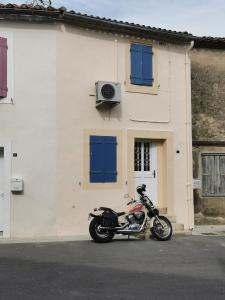 une moto garée devant un bâtiment blanc dans l'établissement Maison cocooning, à Roubia