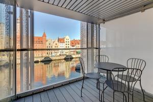 a balcony with a table and chairs and a view of a river at Downtown Apartments Granaria Premium Riverside & Parking in Gdańsk
