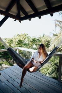 a woman sitting in a hammock on a porch at Villa Pescadores Tulum in Tulum