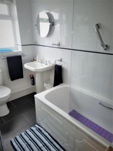 Baño blanco con bañera y lavamanos en Smitten House 4 Bedroom RHYL, en Rhyl