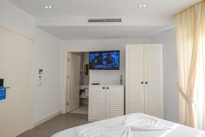 - une chambre blanche avec un lit et une télévision murale dans l'établissement Blue Boutique Hotel, à Dhërmi