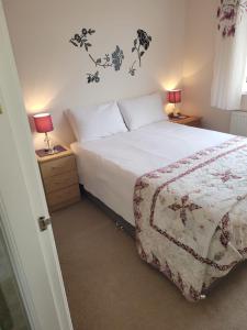 a bedroom with a bed and two night stands with lamps at Smitten House 4 Bedroom RHYL in Rhyl