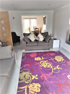 拉爾的住宿－Smitten House 4 Bedroom RHYL，客厅配有沙发和紫色地毯