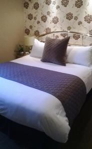 a bed with a white comforter and pillows at Albany House in Penrith