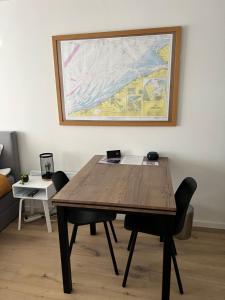une table en bois avec des chaises et un tableau mural dans l'établissement Cosy Studio Testerep , Newly Renovated, à Ostende
