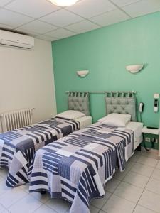 2 camas en una habitación con paredes azules en Carry Hotel, en Carry-le-Rouet