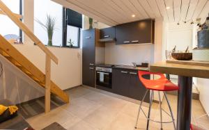 eine Küche mit schwarzen Schränken und einem roten Stuhl in der Unterkunft Le Studio Compostelle by Maison Brasseurs d'Etoiles in Lüttich