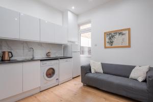 Comfortable flat in Hammersmith في لندن: غرفة معيشة مع أريكة وغسالة