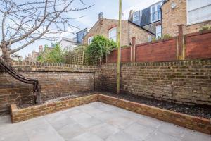a brick retaining wall with a wooden fence at Comfortable flat in Hammersmith in London