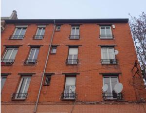 a tall red brick building with white windows at Solo traveler's best stop near Paris in Bagnolet