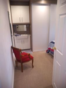 a room with a red chair and a kitchen at Smitten House 4 Bedroom RHYL in Rhyl