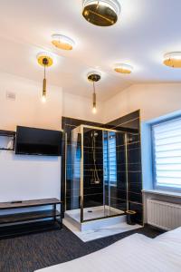 a room with a glass shower and a tv at GLAMOUR - Restaurant & SPA in Przeźmierowo