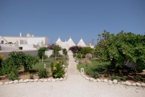 a garden with white buildings and trees and plants at Trulli sul Mare Forcatella in Savelletri di Fasano