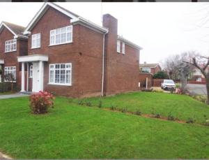 a brick house with a lawn in front of it at Smitten House 4 Bedroom RHYL in Rhyl