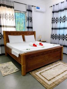 Un dormitorio con una gran cama de madera con flores rojas. en Tamu House Pajé Beach, en Paje