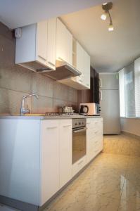 een keuken met witte kasten en een koelkast bij Dracula Adventure Tours Accommodation in Boekarest