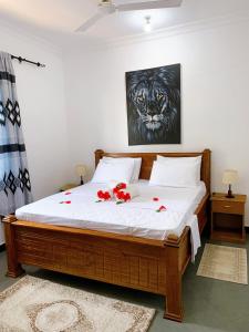a bedroom with a bed with red flowers on it at Tamu House Pajé Beach in Paje