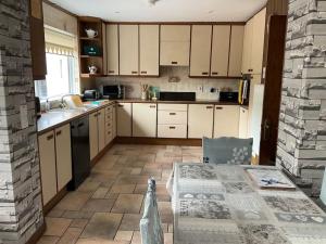a kitchen with white cabinets and a table in it at Umry Lodge in Antrim