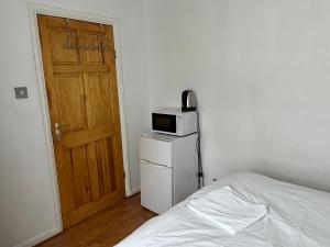 um quarto com uma cama e um micro-ondas em cima de um frigorífico em Large Double Bedroom with free on site parking em Kingston upon Thames