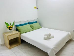 ein weißes Bett mit Hut auf einem Nachttisch in der Unterkunft KL Rinas Best Homestay at Bukit Bintang City Center in Kuala Lumpur