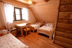 a bedroom with two beds and a table and a desk at Domek Łemkowski in Ustrzyki Dolne