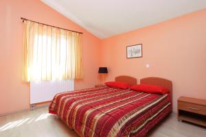 um quarto com uma cama com almofadas vermelhas e uma janela em Apartments by the sea Arbanija, Ciovo - 19576 em Trogir