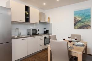 eine Küche mit weißen Schränken und einem Tisch mit Weingläsern in der Unterkunft Apartments by the sea Puntinak, Brac - 19491 in Selca