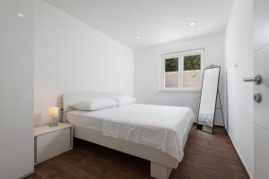 ein weißes Schlafzimmer mit einem Bett und einem Spiegel in der Unterkunft Apartments by the sea Puntinak, Brac - 19491 in Selca