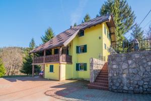 a yellow house with a balcony and a stone wall at Family friendly house with a parking space Lokve, Gorski kotar - 19457 in Lokve