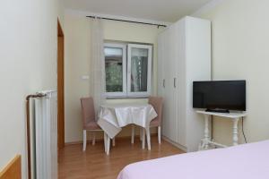 a room with a table and chairs and a television at Apartments with a parking space Kostrena, Rijeka - 19470 in Kostrena