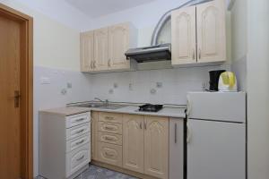 a kitchen with white cabinets and a white refrigerator at Apartments with a parking space Kostrena, Rijeka - 19470 in Kostrena
