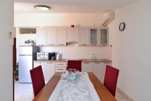 kuchnia z białymi szafkami i stołem z czerwonymi krzesłami w obiekcie Apartments with a parking space Fazana - 19641 w Fažanie
