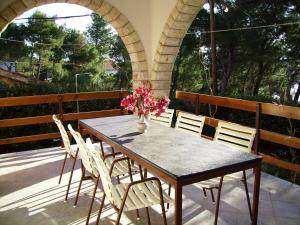 - une table avec des chaises et un vase de fleurs sur la terrasse dans l'établissement Apartments by the sea Basina, Hvar - 19668, à Vrbanj