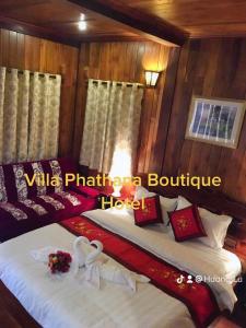 two twin beds in a room with wooden walls at Villa Phathana Boutique Hotel in Luang Prabang