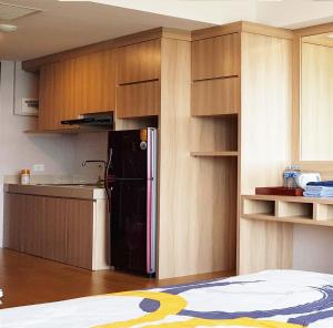 a kitchen with a black refrigerator and wooden cabinets at U Residence Tower2 Supermal by Lippo Karawaci in Klapadua