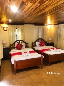 um quarto com 2 camas com lençóis vermelhos e brancos em Villa Phathana Boutique Hotel em Luang Prabang