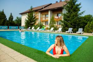 a woman sitting on the grass near a swimming pool at VILA DORULUI in Molovata Nouă +20 photos