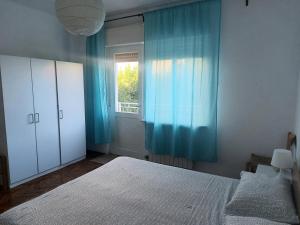 a bedroom with a bed and a window with blue curtains at Apartment Iva Pula in Banjole